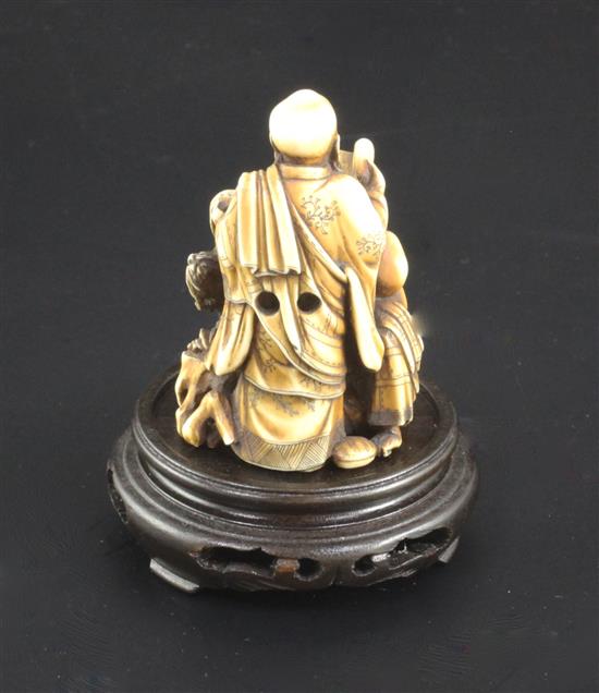 A Japanese ivory okimono netsuke of Handaka Sonja invoking a dragon with another rakan, Meiji period, height 6cm, wood stand